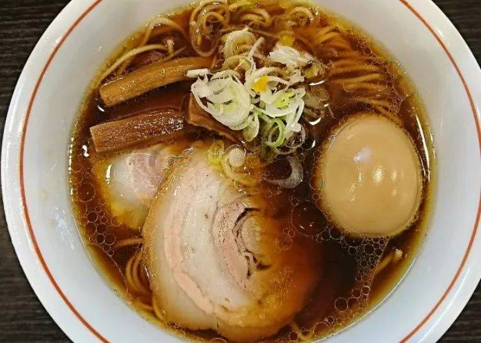 A bowl of ramen at Ramen Hayato, featuring thick slices of pork, bamboo shoots, spring onions and a soft-boiled egg on a bed of ramen noodles.